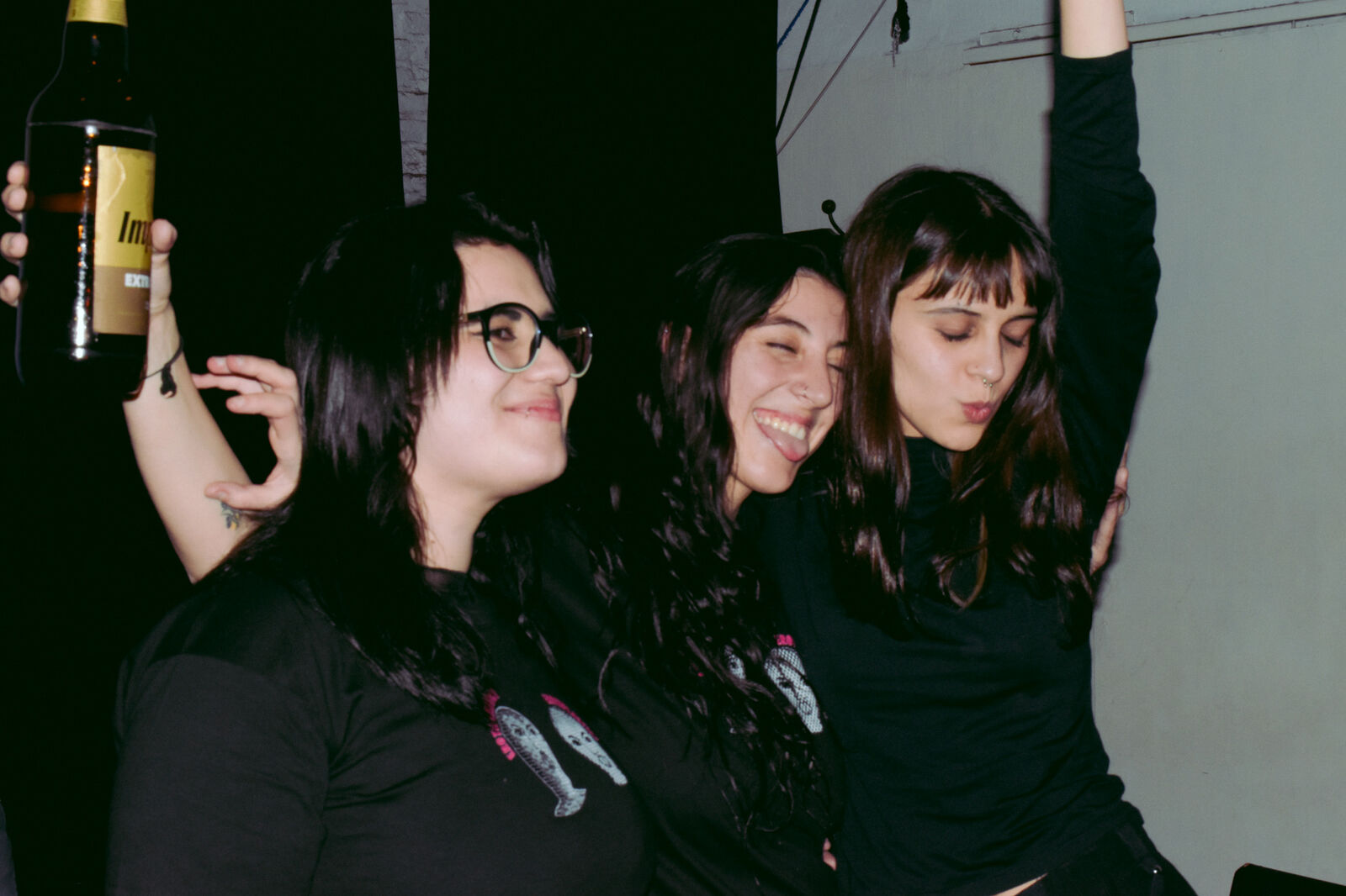 Tres chicas abrazadas en una fecha, con remeras negras estampadas