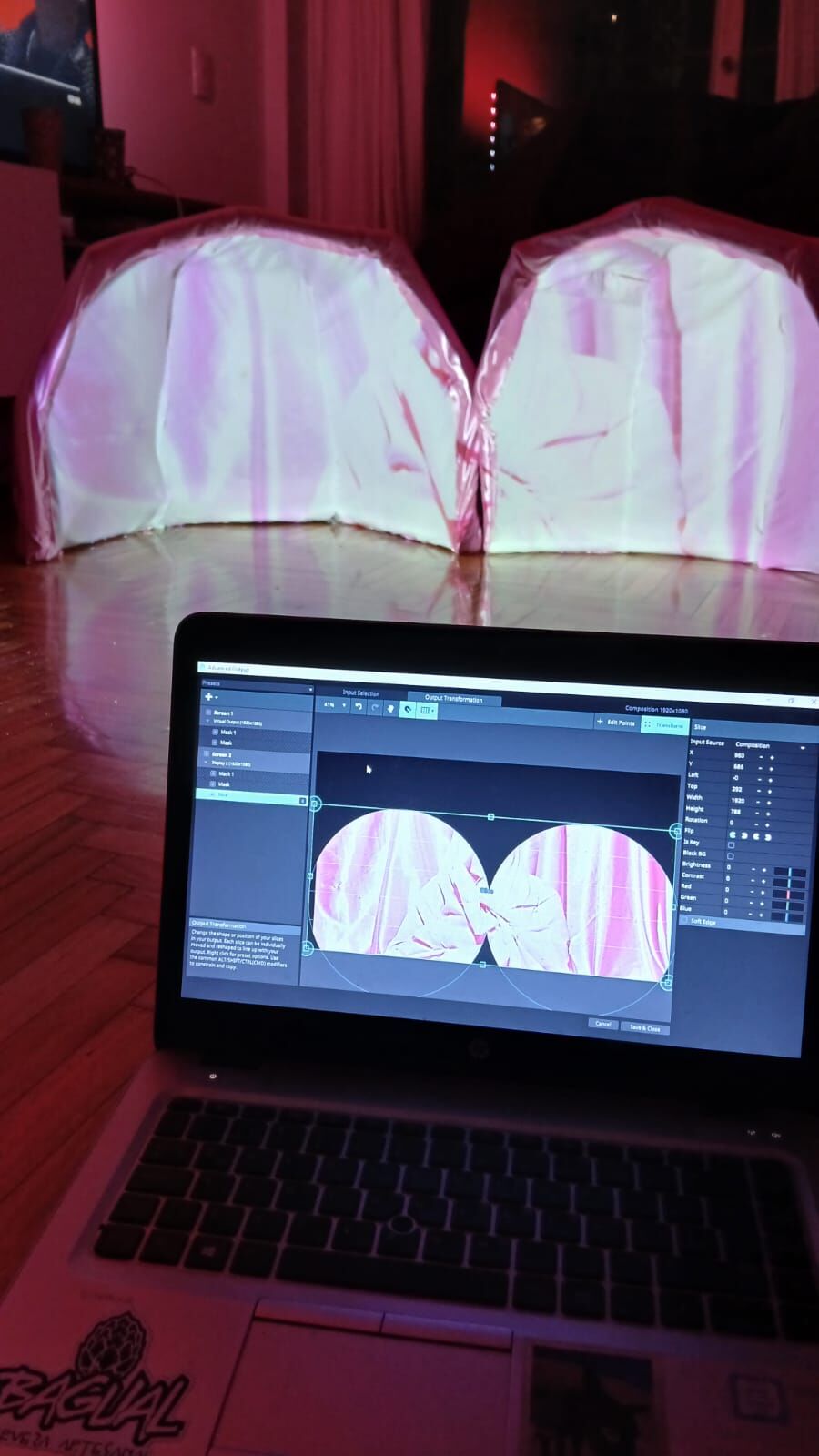 Maqueta del domo con una proyección rosa y, adelante, la computadora con el mapping en Resolume